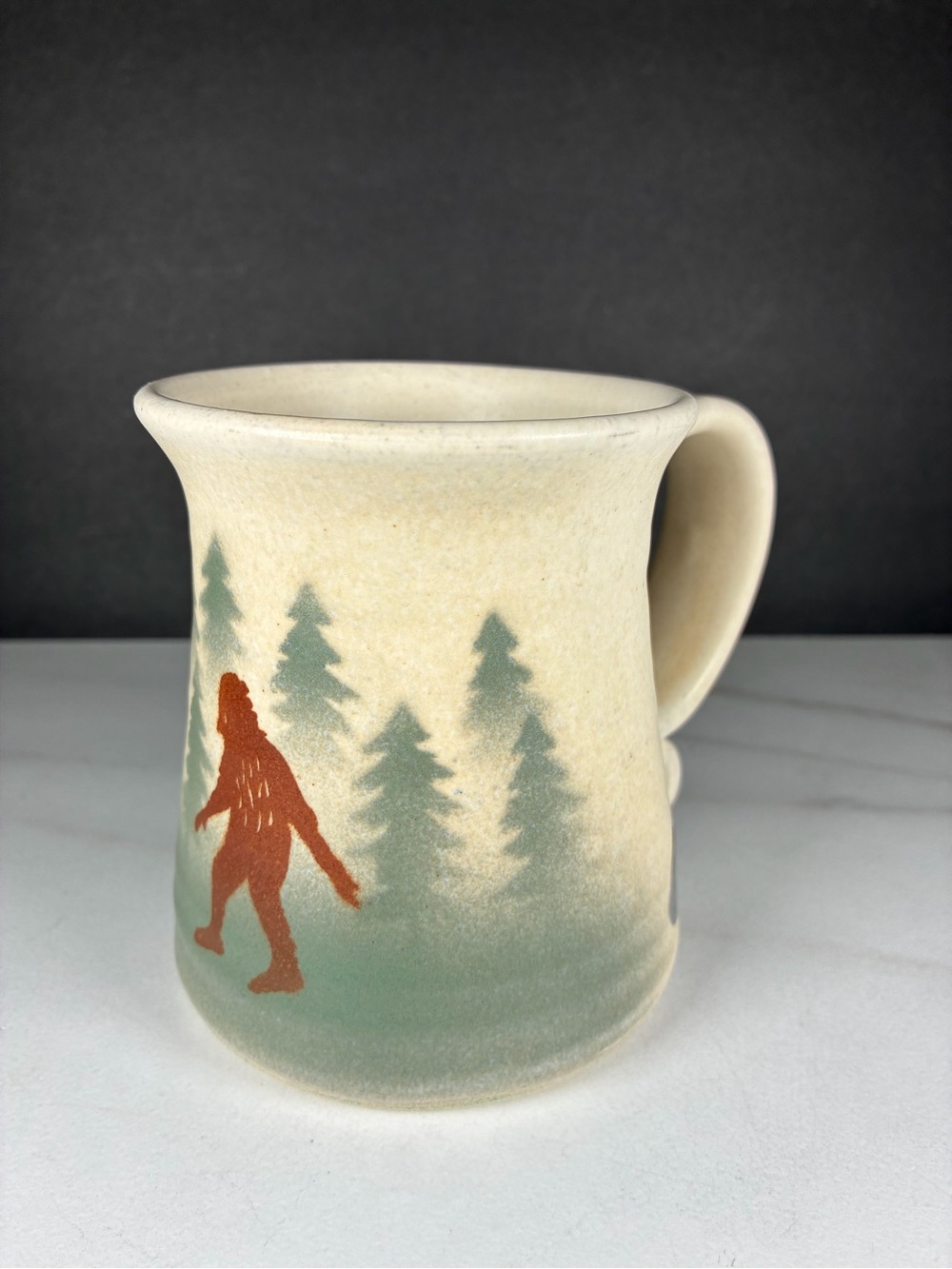 Handmade in Oregon Cream Ceramic Mug with Green Forest and Rust Sasquatch